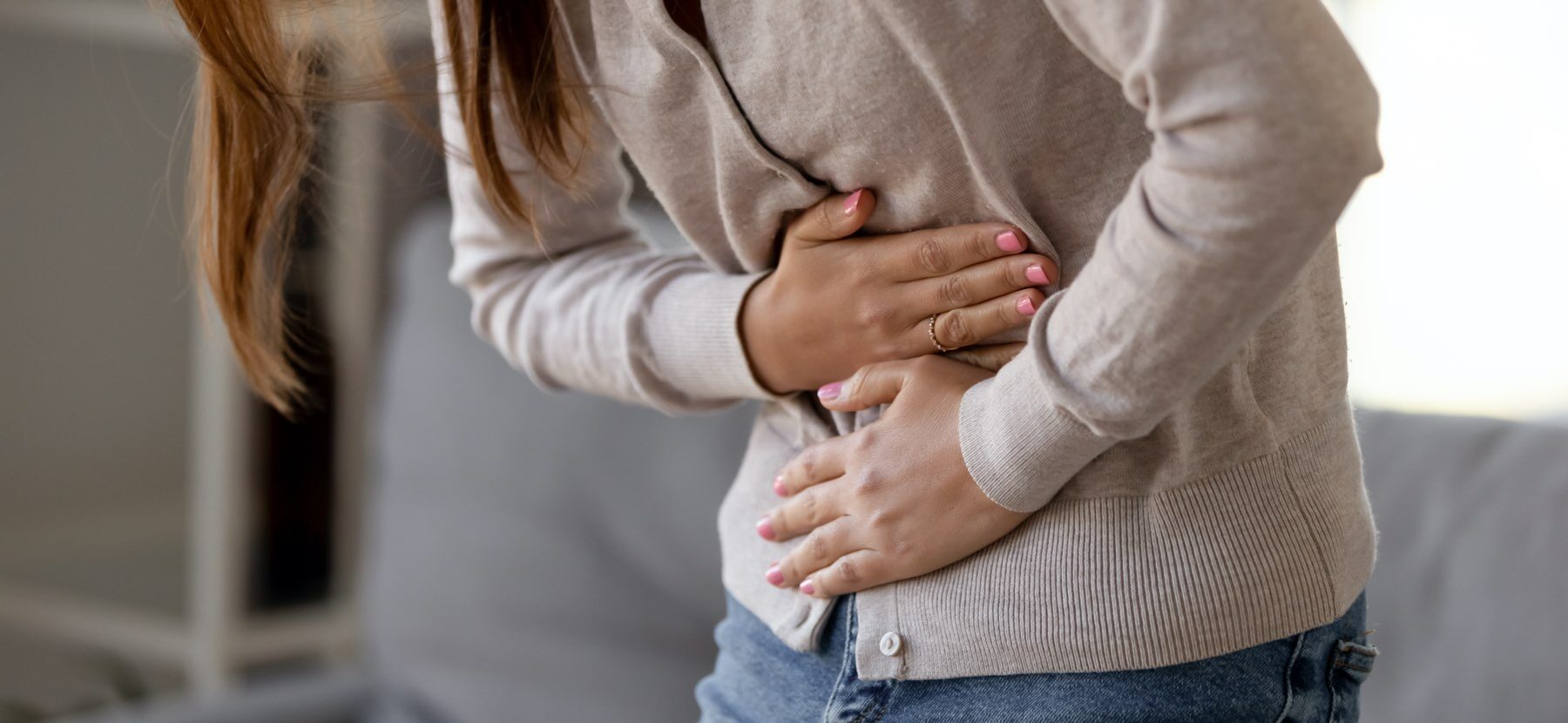 Nahrungsmittelunverträglichkeit: Frau fasst sich vor Schmerzen an den Bauch